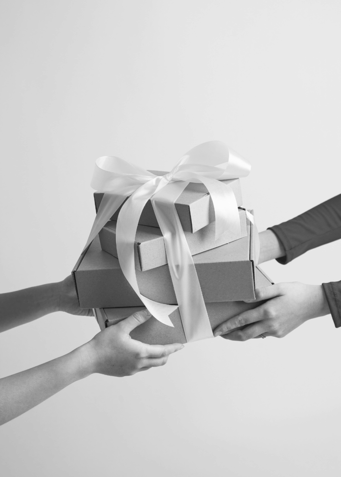 Dos manos sosteniendo una caja de regalo con un lazo decorativo.