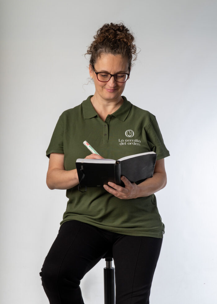 Mujer con camiseta de la empresa "la semilla del orden" escribiendo en una libreta